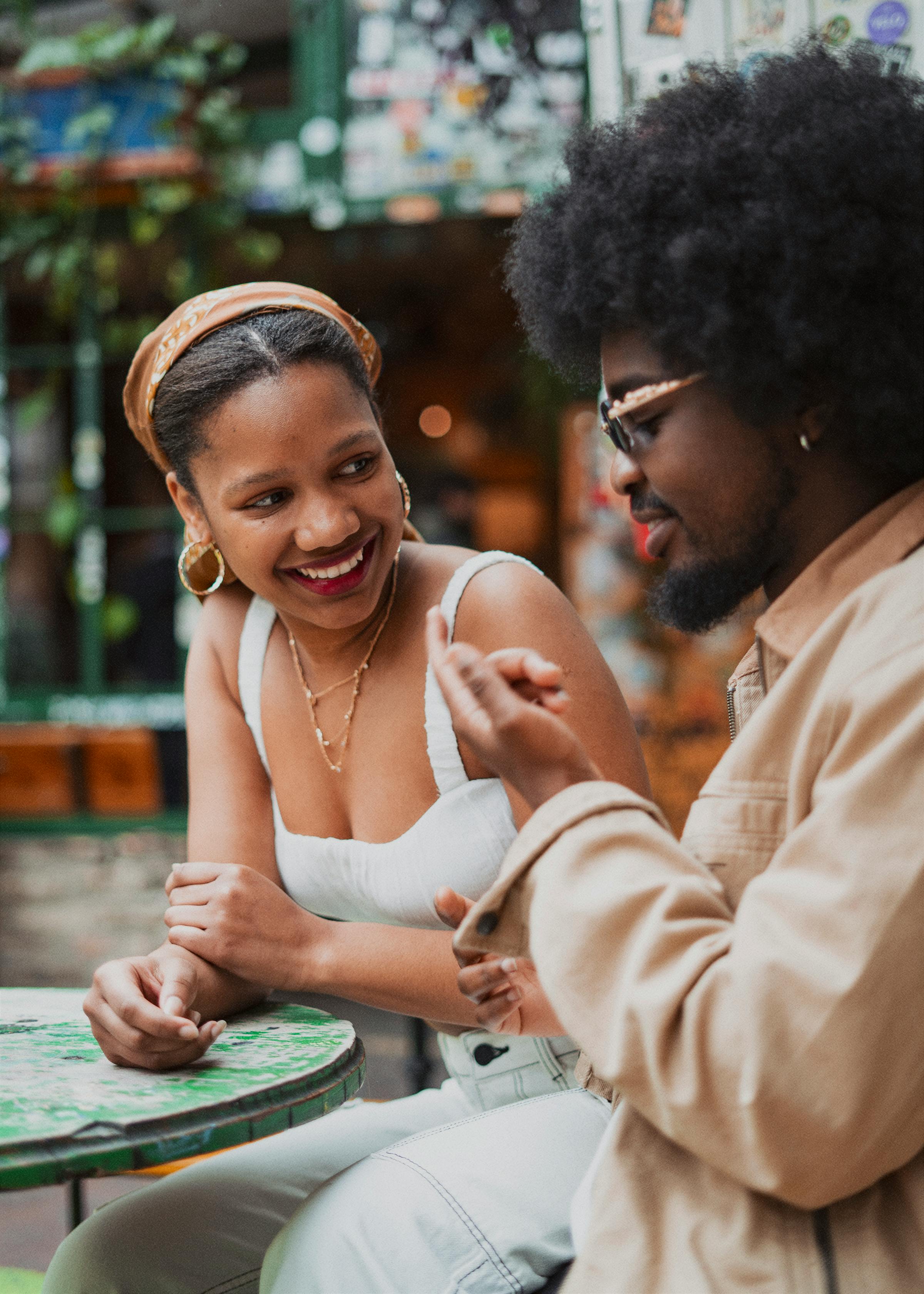 Black couple chatting at outdoor table.